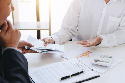 Businessman bribing male colleague at desk in office