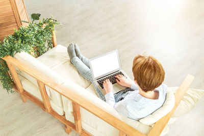 A young girl is lying on the sofa with a laptop