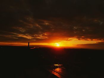 Scenic view of silhouette landscape against dramatic sky during sunset