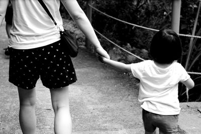 Low section of mother and daughter walking outdoors