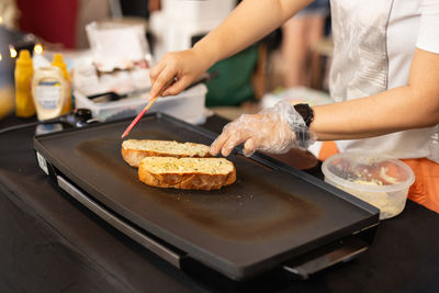 Woman cooking garlic bread with and herbs on iron pan.