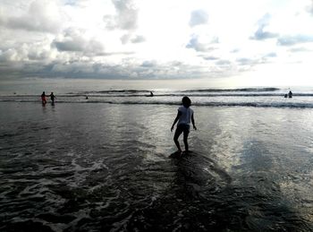 Woman wading in sea against sky