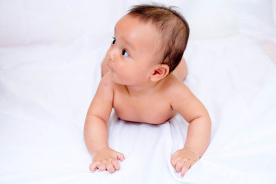 Close-up of cute baby girl in bed