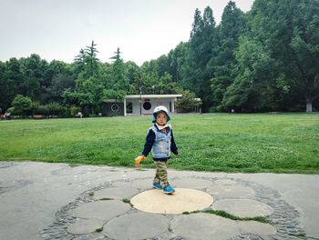Portrait of smiling boy standing on field against trees