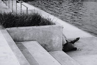 High angle view of man siting on footpath by river