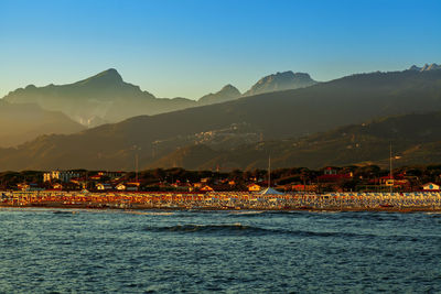 Scenic view of sea by mountains against clear sky