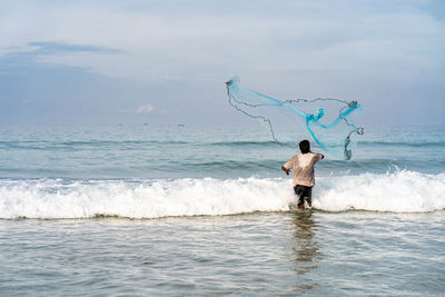 Full length rear view of person at sea shore against sky