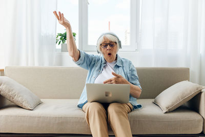 Young woman using laptop while sitting on sofa at home