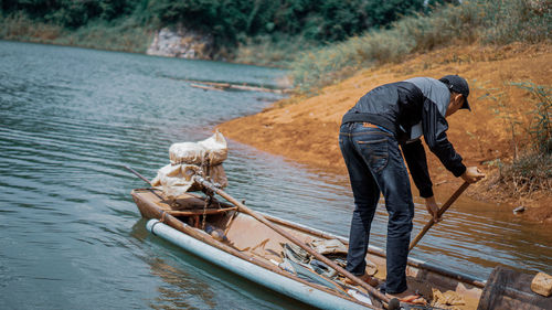 Rear view of man standing on boat in lake