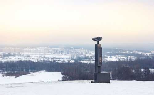 Built structure on snow covered landscape against sky during sunset