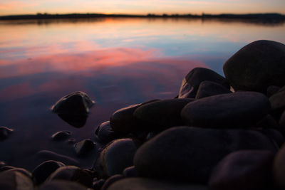 Close-up of stones in lake at sunset