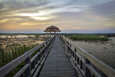 Pier over sea against sky during sunset