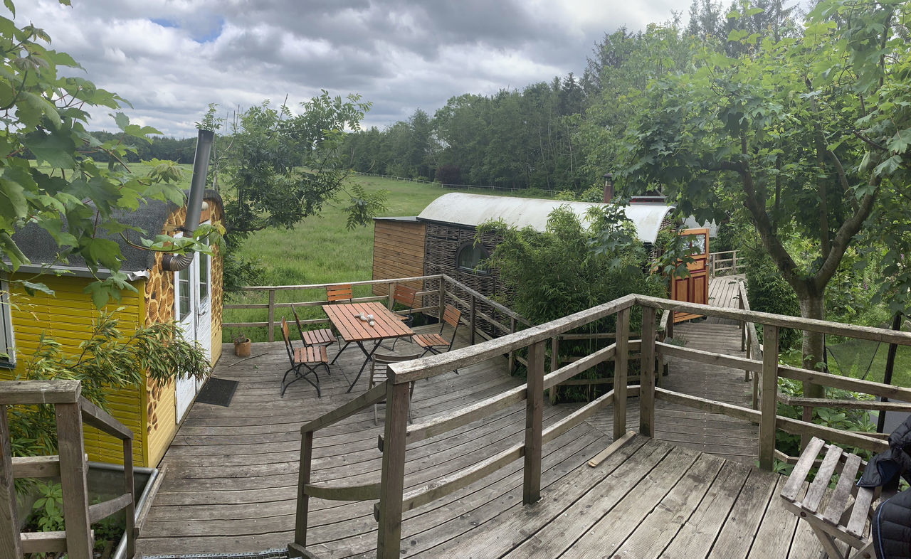 EMPTY CHAIRS AND TABLE AGAINST TREES AND BUILDINGS