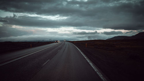 Road passing through landscape against cloudy sky