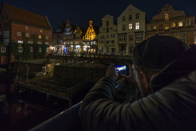 Man photographing illuminated city at night