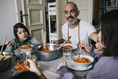Happy father eating spaghetti with children at dining table