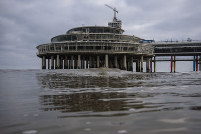 View of building by sea against cloudy sky