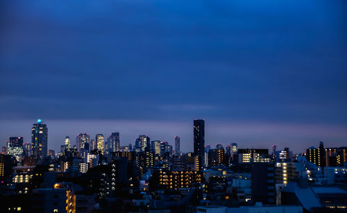 Illuminated buildings in city against sky at night