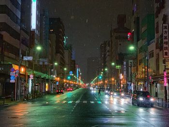 Illuminated street amidst buildings at night