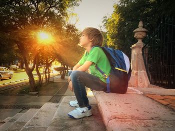 Boy looking at camera while sitting on tree