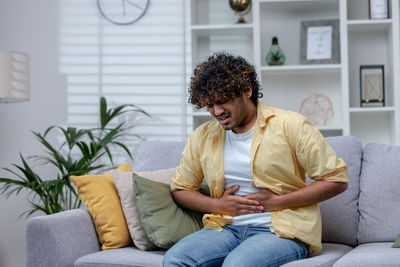 Young man sitting on sofa at home