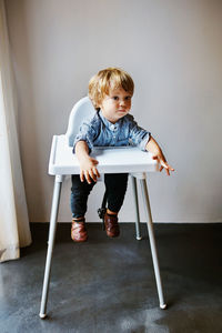 Full length of boy sitting on chair at home