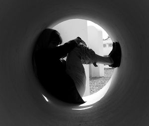 Side view of woman sitting in concrete pipe