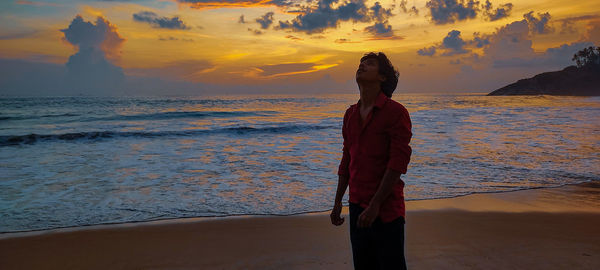 Woman standing at beach during sunset
