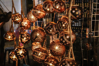 Low angle view of illuminated lighting equipment hanging at store