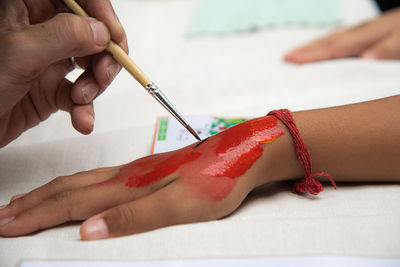 Midsection of woman holding red finger