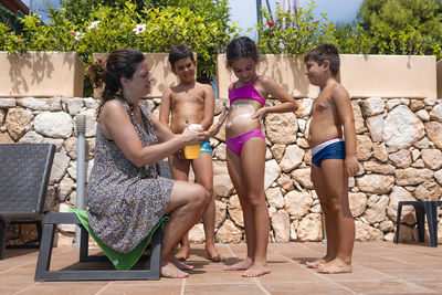 Mom smears his children with sunscreen on the pool