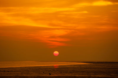 Scenic view of sea against dramatic sky during sunset