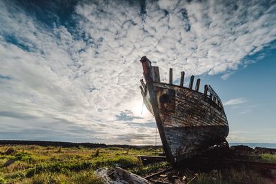 Abandoned boat in sea against sky