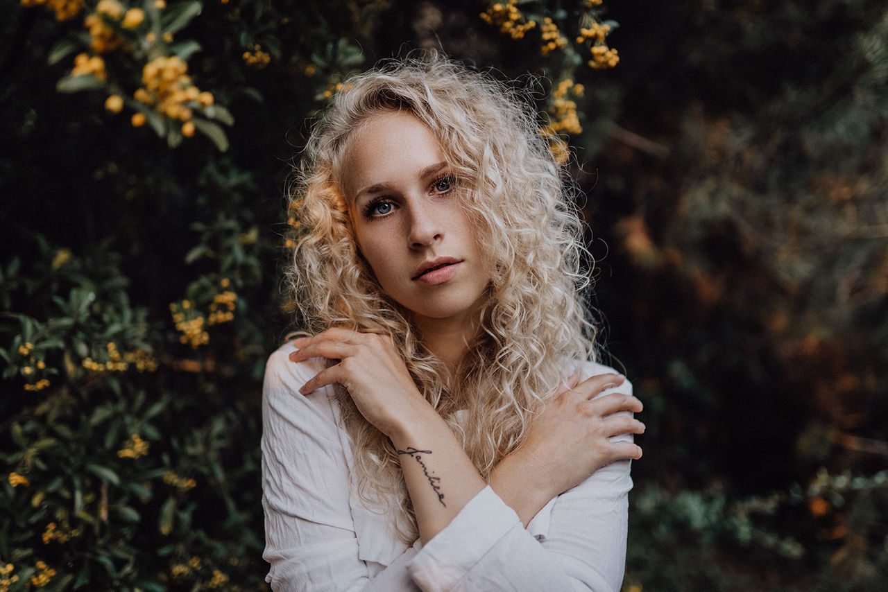 one person, hair, young adult, blond hair, leisure activity, portrait, plant, front view, real people, focus on foreground, young women, lifestyles, long hair, tree, women, nature, hairstyle, beautiful woman, outdoors, contemplation