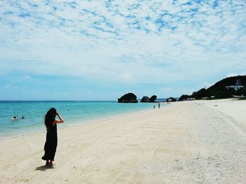 Woman standing at beach against sky