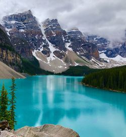 Scenic view of lake by snowcapped mountains against sky