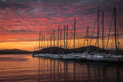 Boats moored at harbor during sunset