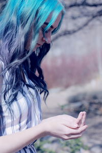 Side view of young woman with dyed hair cupping hands