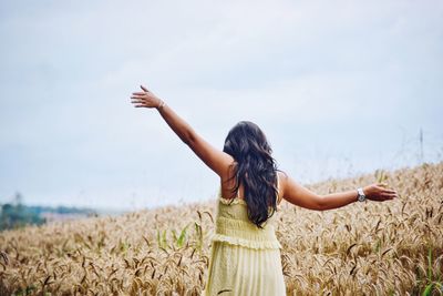 Rear view of woman standing on field against sky