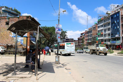 Cars on road by buildings against sky in city