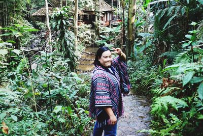 Portrait of woman standing by tree in forest