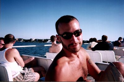 Portrait of shirtless young man wearing sunglasses traveling in ferry against clear blue sky