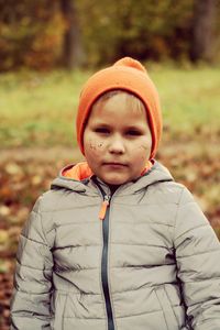A boy in orange hat dirty face outdoors in the park