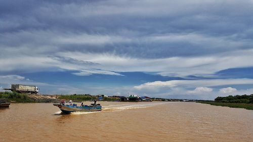 Motorboat sailing in river against sky