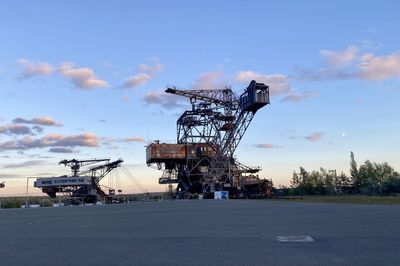 Ferris wheel by factory against sky
