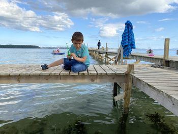 Full length of boy sitting on pier