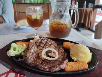 Rib eye steak with mashed potato and vegetables served on a hot plate