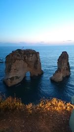 Rock formation in sea against clear sky