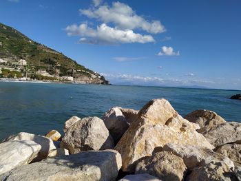 Rocks by sea against blue sky