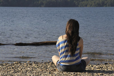 Rear view of woman sitting on beach